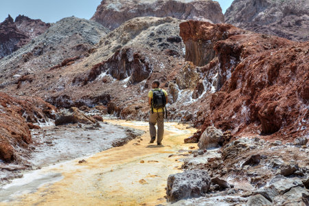 Hormuz Island, Hormozgan Province, Iran - 17  april, 2017: Iranian Island of Hormuz in Persian Gulf, One traveler walks along the yellow river in the salt valley.のeditorial素材