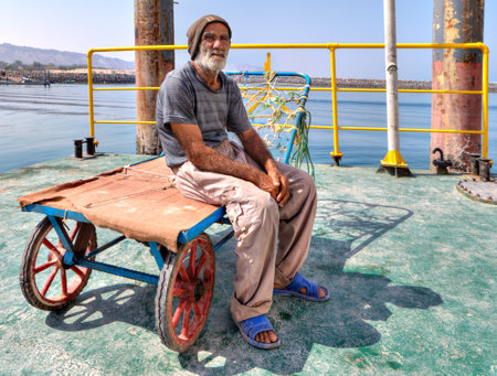 Hormuz Island, Hormozgan Province, Iran - 17  april, 2017: One elderly Iranian port loader sits on his trolley on the pier of the island of Ormuz.のeditorial素材