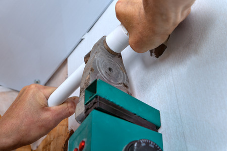 Plastic pipe welding machine, plumber with welding machine connect plastic pipes installation of a water pipe on the wall, hands working close-up.の写真素材