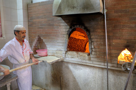 Fars Province, Shiraz, Iran - 18 april, 2017: The baker prepares to put the dough into a stone bakery oven.のeditorial素材