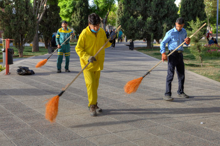 Fars Province, Shiraz, Iran - 19 april, 2017: Three janitors sweep the road in the city recreation park using brooms.のeditorial素材