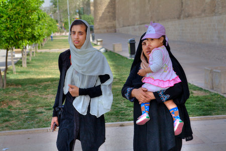 Fars Province, Shiraz, Iran - 19 april, 2017: A Muslim family, a young woman, a mature woman and a little girl are walking along city streets near the Karim Khan castle.のeditorial素材