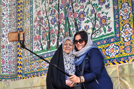 Fars Province, Shiraz, Iran - 19 april, 2017: Two islamic women wearing muslim dress make selfie in  inner courtyard of the Vakil mosque, using selfie stick.のeditorial素材