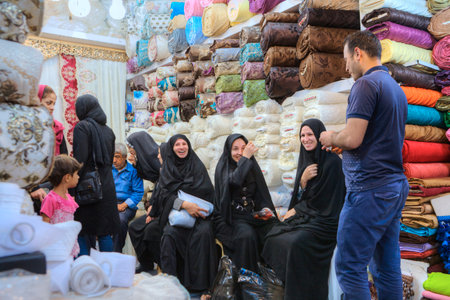 Fars Province, Shiraz, Iran - 19 april, 2017:  Several Iranian women in black Muslim clothes rest and laugh in the tissue department of the central market.のeditorial素材