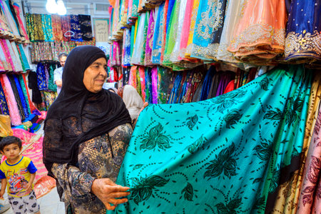 Fars Province, Shiraz, Iran - 19 april, 2017:  One unknown elderly Iranian Muslim woman chooses a cloth in the textile shop of the Grand Bazaar.のeditorial素材