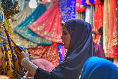 Fars Province, Shiraz, Iran - 19 april, 2017:  One young Iranian woman wearing in hijab choose the fabric for purchase in a textile shop in the bazaar.のeditorial素材