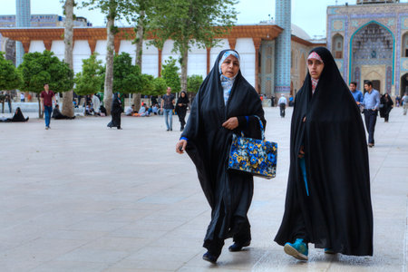 Fars Province, Shiraz, Iran - 19 april, 2017:  The inner courtyard of the Shah Cheragh Shrine, two Muslim women dressed in a chador, stroll after a prayer.のeditorial素材