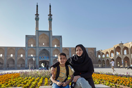 Yazd, Iran - April 21, 2017:  Woman in the Islamic chador and her son sitting on the bench in front of Amir Chakhmaq Complex.のeditorial素材