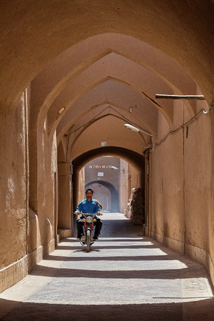 Yazd, Iran - April 21, 2017: An unknown young Iranian man is riding a moped along a narrow arched street.のeditorial素材
