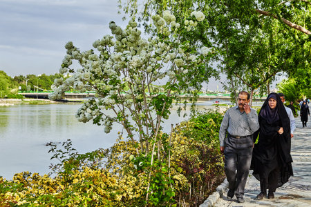 Isfahan, Iran - April 24, 2017: A mature Iranian couple walks along the embankment of the city river.のeditorial素材