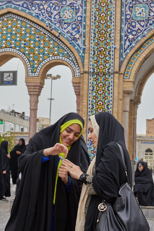Tehran, Iran - April 27, 2017: Iranian women in hijabs are watching photos in smartphone near the...