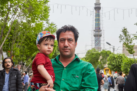 Tehran, Iran - April 27, 2017: an Iranian man with his little son in his arms is walking down the street of Shahre Rey area.のeditorial素材