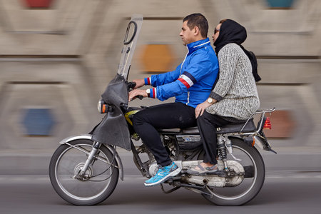 Tehran, Iran - April 28, 2017:  A woman in a hijab sits behind a motorcyclist while traveling on a highway, camera panning for motion blur  in  background.のeditorial素材