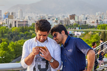 Tehran, Iran - April 28, 2017: Nature Bridge, Two Iranian tourists are looking at the smartphone screen, standing on the Tabiat bridge, against the backdrop of the cityscape.のeditorial素材