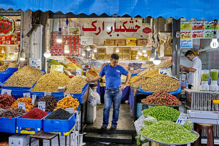 Tehran, Iran - April 29, 2017: grocer stands in the middle of his store with dried and fresh fruits.のeditorial素材