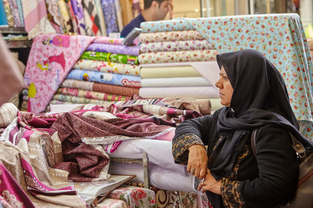 Tehran, Iran - April 29, 2017: Iranian woman in religious veil is looking for fabrics in a store with fabrics on grand bazaar.のeditorial素材