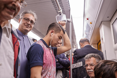 Tehran, Iran - April 29, 2017: Iranian men of different ages ride the subway, one of them listens to music on headphones, another stands and smiles.のeditorial素材