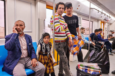 Tehran, Iran - April 29, 2017: Iranian men and a girl in a hijab ride on a subway train, an elderly man is talking on the phone.のeditorial素材