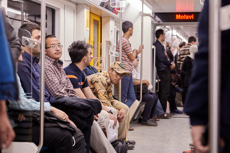 Tehran, Iran - April 29, 2017: Iranian men stand and sit in the new modern underground train.