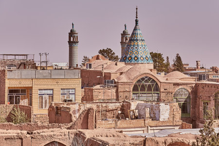 Kashan, Iran - April 26, 2017: The roofs of historic houses made of clay bricks and the conical dome of the Sultan Ahmad mosque with two minarets.のeditorial素材