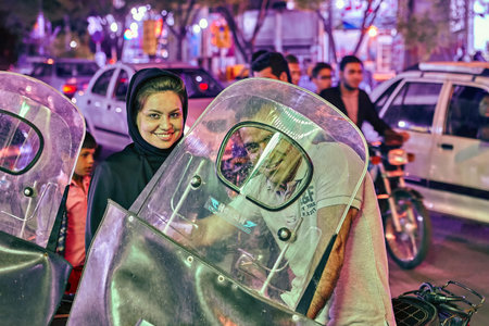Kashan, Iran - April 25, 2017: Iranian family in a parking lot in the evening, a woman in a hijab is...