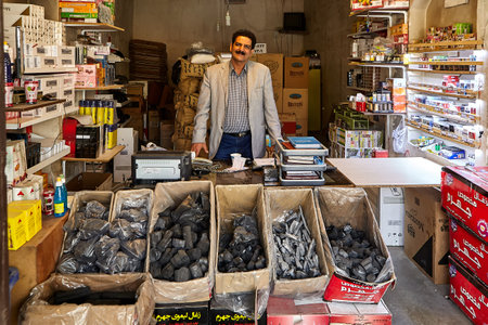 Kashan, Iran - April 27, 2017: A street vendor of tobacco and charcoal for hookah stands in his tobacco shop.のeditorial素材