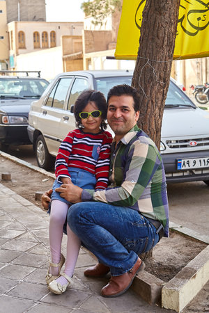 Kashan, Iran - April 27, 2017: A little girl in sunglasses, and a young man, her father, posing for a photo on a city street.のeditorial素材