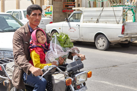 Kashan, Iran - April 27, 2017: Iranian family, father and daughter, ride a motorbike on a city street.のeditorial素材