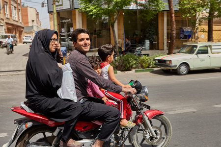 Kashan, Iran - April 27, 2017: Iranian family:  man, woman in a hijab and little boy and girl ride a motorbike on a busy street.のeditorial素材