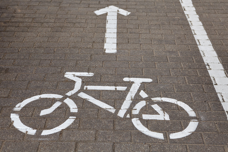 Bicycle road sign and arrow direction on cycling path painted on sidewalk.の写真素材