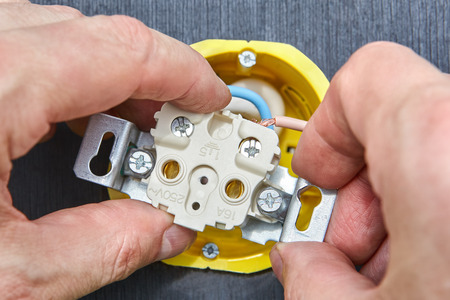 Household  power line, fastening of electric socket to patress box, hands of electrician close-up.の写真素材