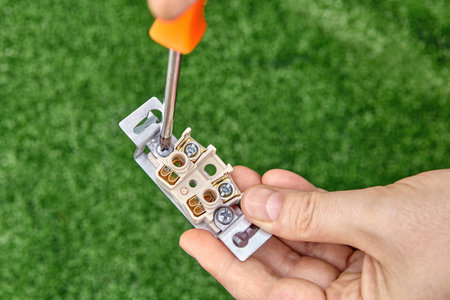 The electrician loosens the bolt of the electrical outlet, close-up.の写真素材