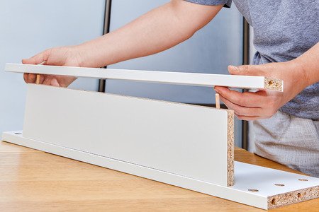 Assembly of wooden furniture, installer putting together two chipboard with furniture connected fittings such as wooden dowel pin.の写真素材