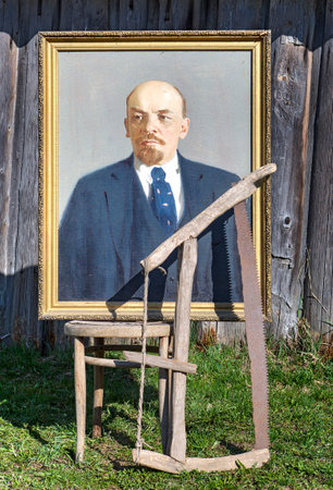 Karelia, Russia - May 1, 2016: Exposed on the street of Vladimir Lenin portrait oil on canvas in a gilt frame, next to the ancient and rusty hand saw.のeditorial素材