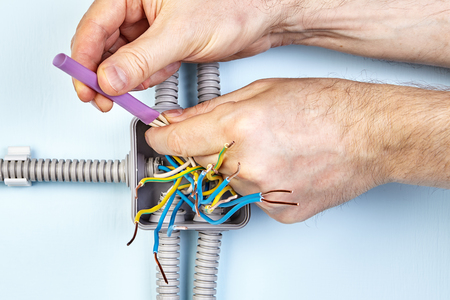 Electrician is using heat shrink tubing for joining ends of wire together for good contact.の写真素材