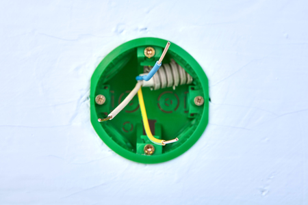 Round electrical box for wall light switch with copper wires inside, electric installation work.の写真素材