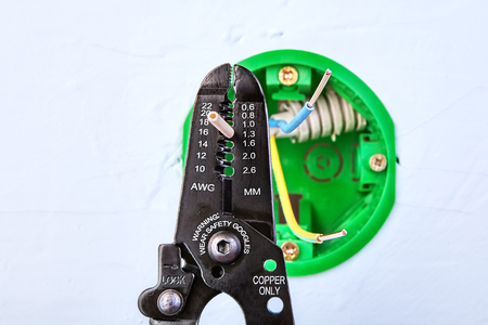 Stripping ends of the wires of round electrical box for wall light switch, electrical work.の写真素材