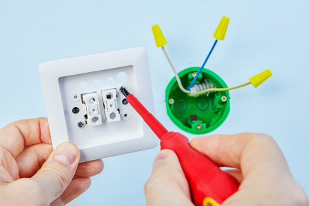 Electrician is installing new double light switch with help of screwdriver.の写真素材