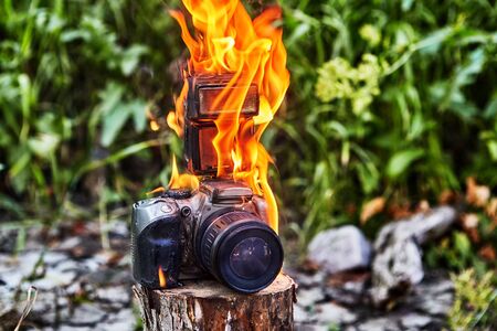 Forest fire destroyed the camera tourists. A camera forgotten in a forest glade ignited, melted, and burned. Fire destroyed the photographers electronic gadget.の写真素材