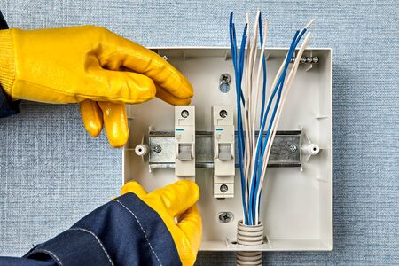 The electric installation work of devices of engineering networks and systems.The electrician carries out wiring services and rewiring consumer unit or fuse box  installation. Mounting circuit breaker.の写真素材