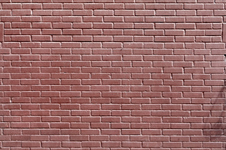 Fence or wall of red decorative brick with a smooth glazed surface. Abstract texture for background.