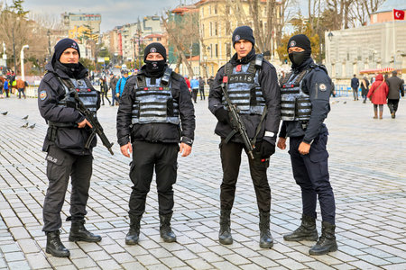 Istanbul, Turkey - February 11, 2020: Four young policemen armed with automatic weapons in uniform and with body armor at Sultanahmet Meydan on a gloomy winter day.のeditorial素材