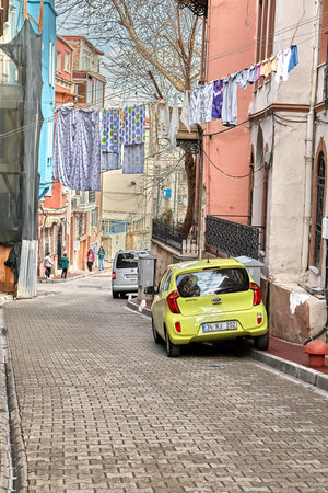 Istanbul, Turkey - February 12, 2020: Balat is the traditional Jewish neighborhood in Fatih district of City center.  A yellow car is parked on a narrow street under a rope on which clothes are dried.のeditorial素材