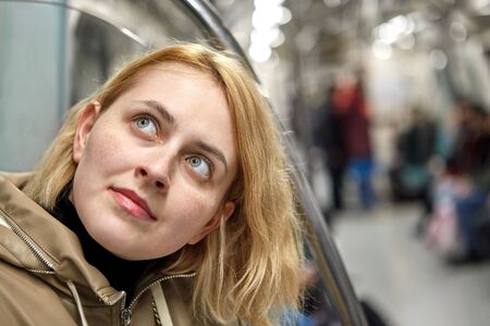 Young pretty white caucasian woman with blond hair is sitting in the subway car in Istanbul.の写真素材