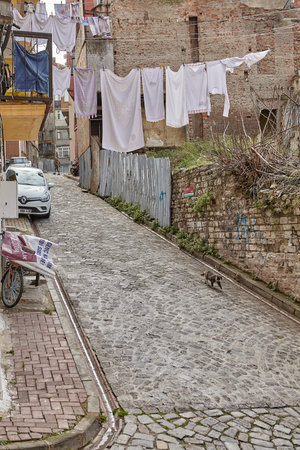 Istanbul, Turkey - February 12, 2020: Narrow Duhanci street in Balat neighborhood or Jewish quarter of Fatih district. Wet clothes hang on a rope stretched over the pavement.のeditorial素材