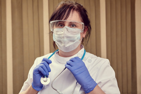 Caucasian female doctor uses personal protective equipment for hands, eyes and respiratory organs...