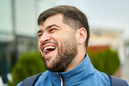 Handsome caucasian man with beard walks outdoors and smiles.