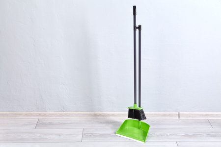 Broom and brush for cleaning flat stands on floor fastened together.