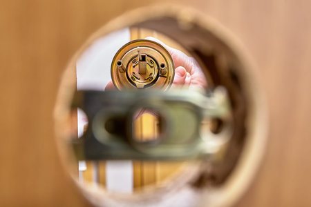 View of doorknob rose with spindle through mounting hole in door and latch assembly.
