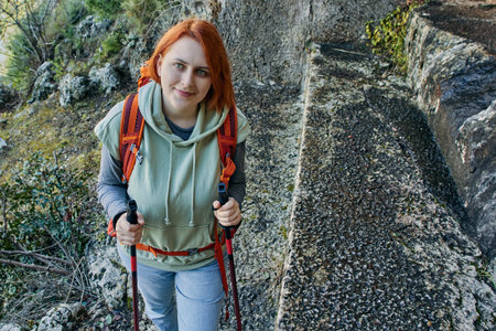 Young white woman uses walking poles during as she climbs to Lycian tombs near resort town of...